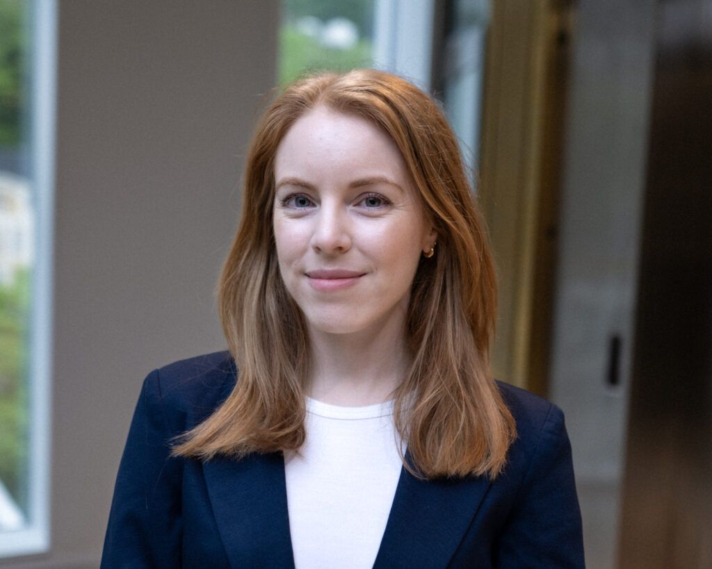 Portrait image of Line Djupvik Andersen. She is wearing a dark blazer and light top, and smiling at the camera.